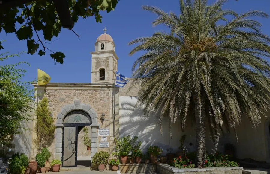 Entrance of Toplou Monastery with bell tower and palm tree in the courtyard